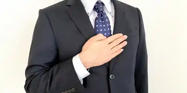 スーツ姿で胸に手を当てている写真