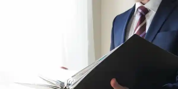 スーツ姿でファイルを持った人の写真